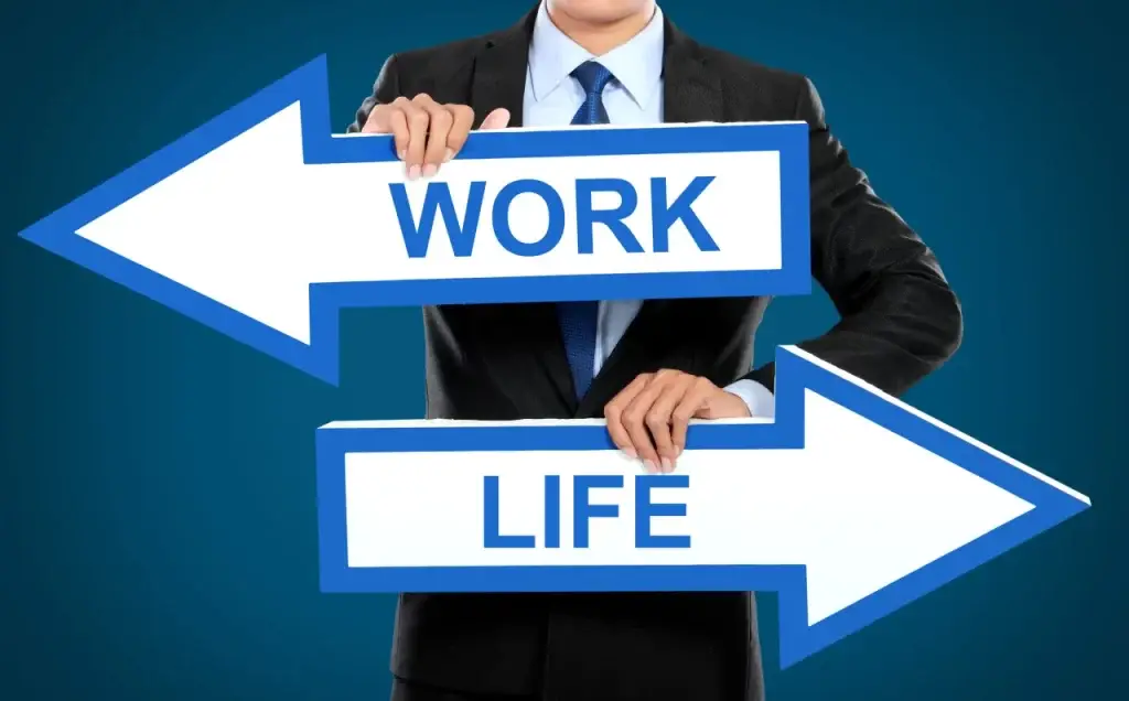 2 Schilder Work Life Balance die von Händen eines Mannes im Anzug gehalten werden.